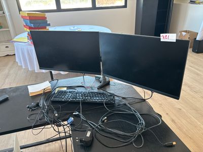 a desk with two monitors and a keyboard on it