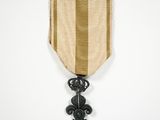 une médaille d'or à laquelle est accroché, sur le côté, un ruban noir et blanc