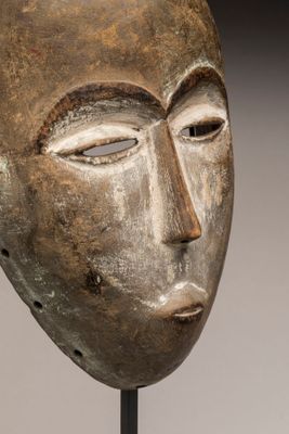 gros plan d'un masque en bois sur un support métallique