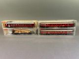 deux trains miniatures rouges et blancs dans des boîtes transparentes posés sur une table