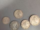 four different types of silver coins on a gray surface