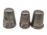three silver thimbles sitting next to each other on a white surface