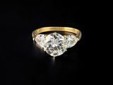 a yellow gold ring with three diamonds on a black background