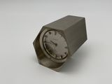 a small metal clock sitting on a white surface
