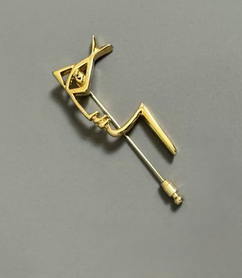 a gold pin with a bird on it on a gray surface