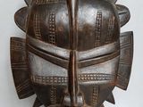 une image d'un masque en bois accroché au mur