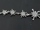 three silver star charms on a black surface with a black background