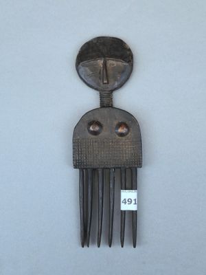 un peigne en métal sur lequel est représenté un visage