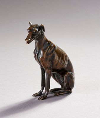 statue en bronze représentant un chien assis sur ses pattes arrière, la gueule ouverte
