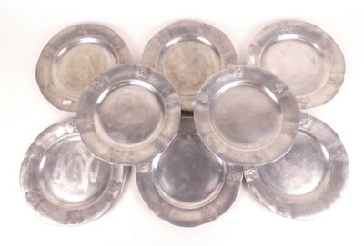 Plusieurs assiettes en argent sont disposées en cercle sur une surface blanche