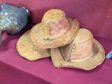 three hats sitting on a red table next to a blue vase
