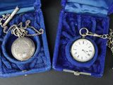 deux montres de poche en argent et une clé dans un étui bleu