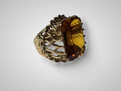 une bague en or sertie d'une grosse citrine entourée d'une chaîne