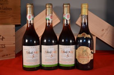 Quatre bouteilles de vin sont alignées sur une table rouge