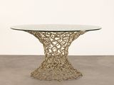 a glass table with a gold metal base and a circular glass top