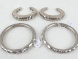three pairs of silver metal hoop earrings sitting on top of a white surface