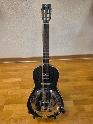 a black guitar sitting on top of a hard wood floor