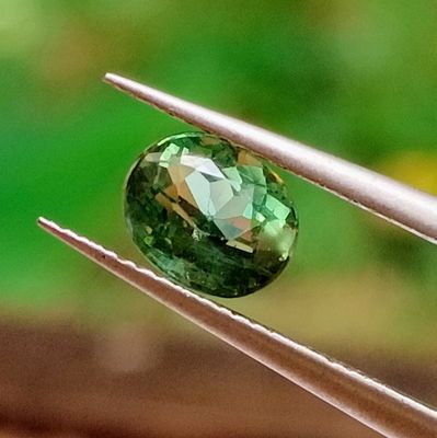 a close up of a green gemstone on a pair of tweets