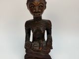 an old wooden statue of a woman sitting on a white surface