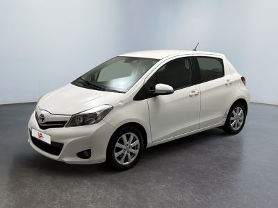 La Toyota Yaris est garée dans une pièce blanche au sol gris.