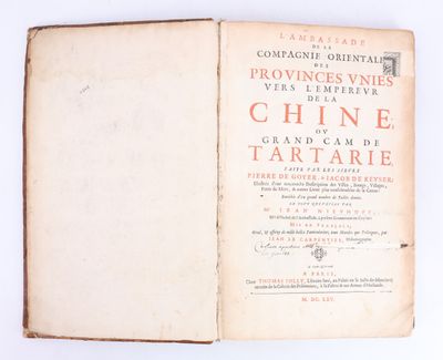 un livre ouvert posé sur une surface blanche, avec des inscriptions rouges dessus