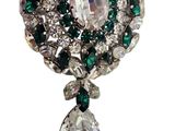 a close up of a brooch with green and white stones