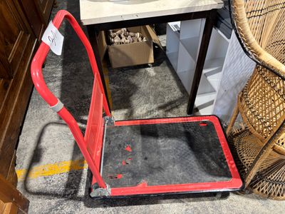 un diable rouge posé par terre à côté d'une chaise