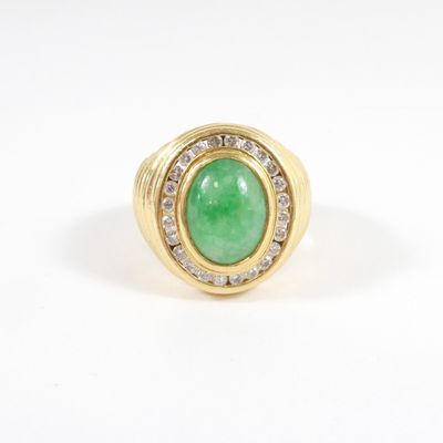 a close up of a ring with a green stone and diamonds