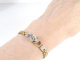 someone is holding a bracelet with a skull on it on a white surface