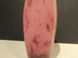 a pink vase sitting on a table with a black background