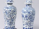 pair of blue and white vases with lids on wooden bases
