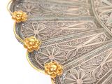 a silver plate with gold flowers on it on a white surface