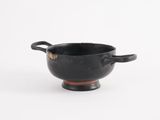 a black cup with a handle on a white surface