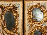 two gold framed mirrors on the wall of a room