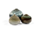 trois vases posés sur une surface blanche