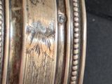 a close up of a silver plate with a bird on it