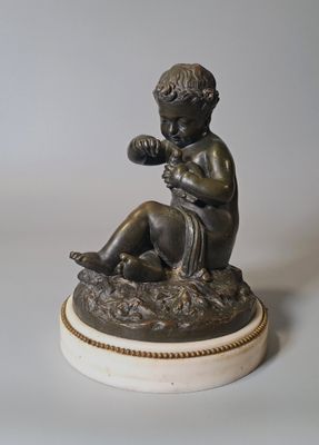 statue d'un garçon assis sur un rocher, une fleur à la main