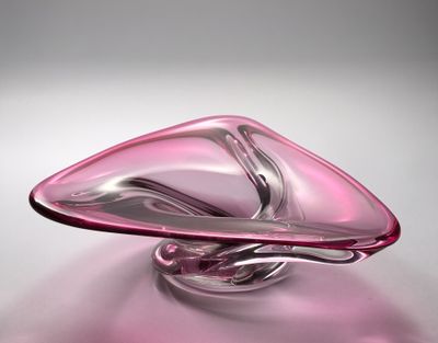 un objet en verre rose orné d'un motif incurvé