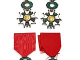 quatre médailles et un ruban rouge sont exposés sur un fond blanc