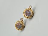 une paire de boucles d'oreilles en or ornées de pierres violettes sur un fond blanc