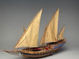 une maquette de bateau à voiles posée sur une surface grise