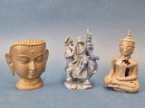 three small statues of buddhas sitting next to each other on a blue surface