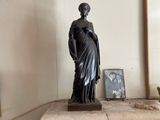 une statue représentant une femme debout sur une cheminée