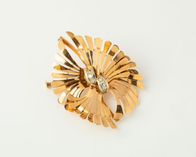 an image of a gold flower brooch with a diamond in the center