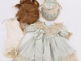 an image of a doll with a hat and dress on a white surface