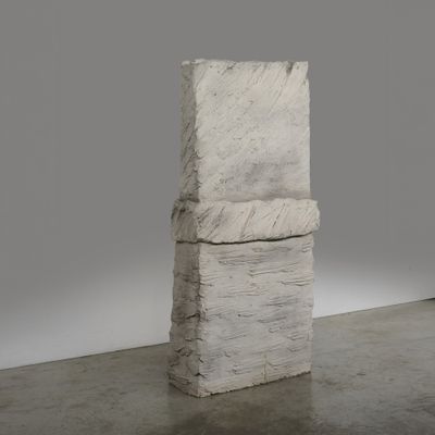 une photo d'une sculpture représentant une pile de livres posée sur un sol en béton