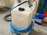 a white container with a blue hose and a blue handle
