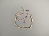 un collier de perles blanches muni d'un fermoir en argent, posé sur une table blanche
