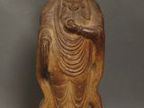 une vieille statue en bois représentant un Bouddha assis sur un rocher