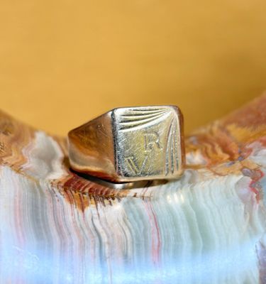 a gold signet ring sitting on top of a piece of marble